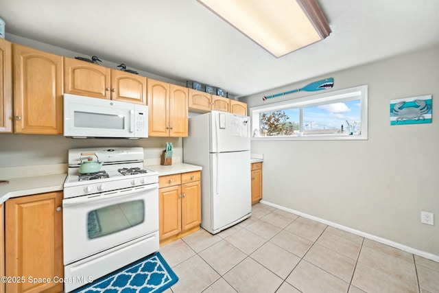 kitchen with light tile patterned floors, baseboards, white appliances, and light countertops