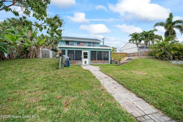 back of property featuring an outdoor structure, fence, a yard, a sunroom, and a storage unit