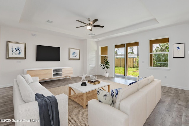 958 Chace Ln NE, Palm Bay, FL 32905 - living area with visible vents, ceiling fan, a tray ceiling, baseboards, and light wood finished floors