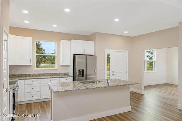 958 Chace Ln NE, Palm Bay, FL 32905 - kitchen featuring stainless steel fridge, light wood finished floors, light stone countertops, an island with sink, and recessed lighting