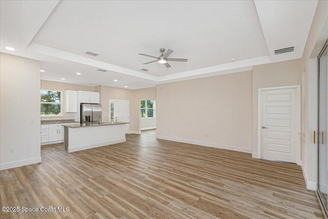958 Chace Ln NE, Palm Bay, FL 32905 - unfurnished living room with a raised ceiling, ceiling fan, light wood finished floors, and recessed lighting