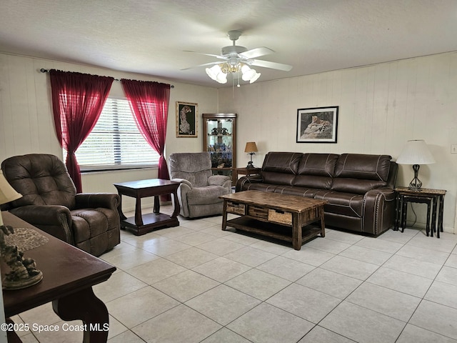 living room featuring light tile patterned floors, ceiling fan, and wooden walls