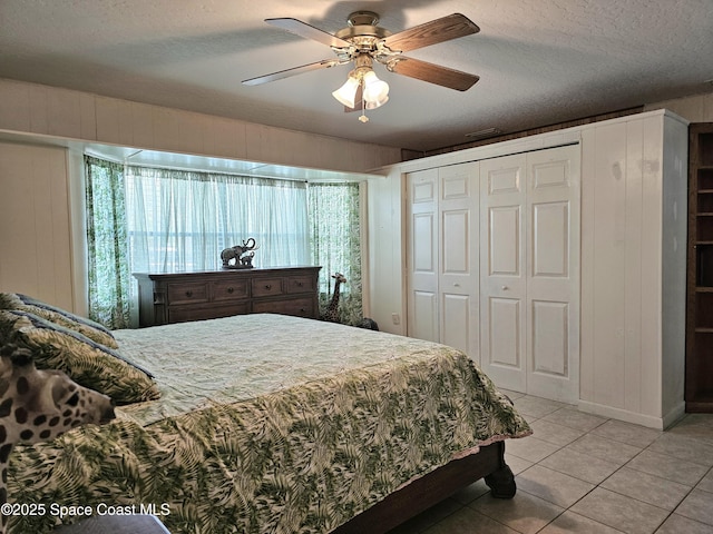bedroom with light tile patterned flooring, a textured ceiling, a closet, and a ceiling fan