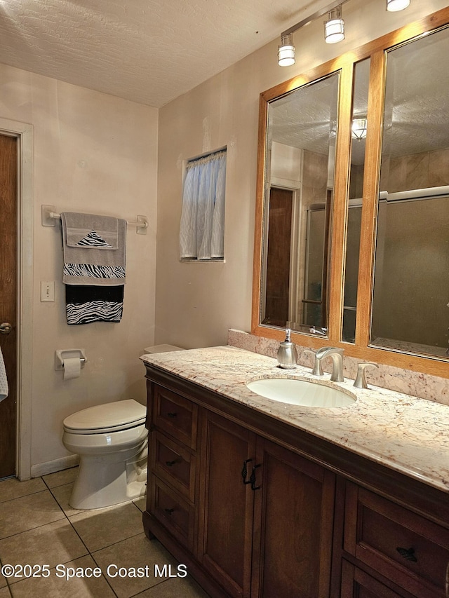 bathroom with tile patterned floors, vanity, toilet, and a textured ceiling