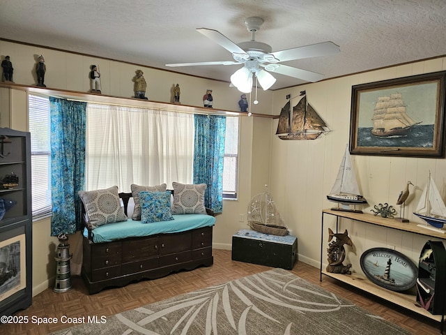 living area featuring a textured ceiling, a ceiling fan, and baseboards