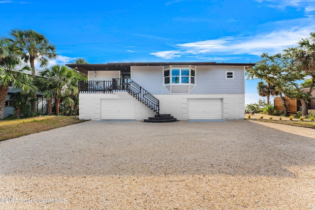 860 S Banana River Dr, Merritt Island, FL 32952 - view of front of home with stairway, brick siding, an attached garage, and gravel driveway