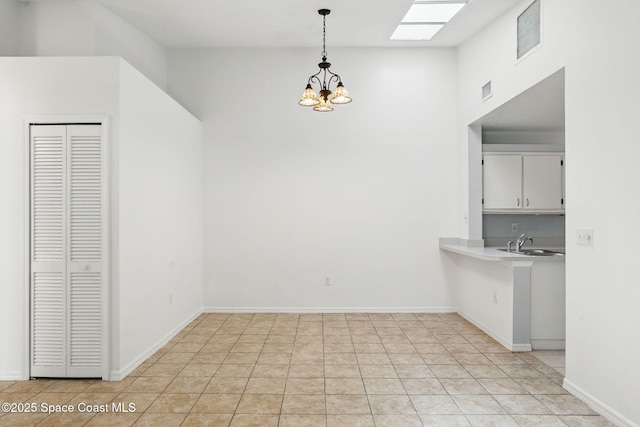 unfurnished dining area featuring baseboards, an inviting chandelier, a sink, and visible vents