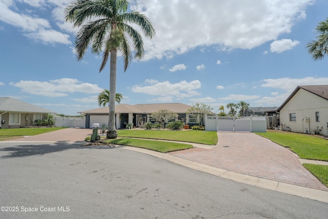 ranch-style house featuring a gate, a front lawn, and decorative driveway