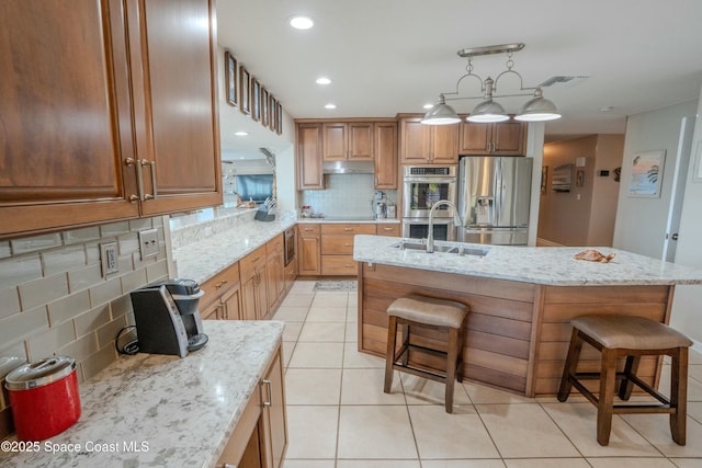 kitchen featuring tasteful backsplash, a kitchen breakfast bar, a sink, stainless steel appliances, and visible vents
