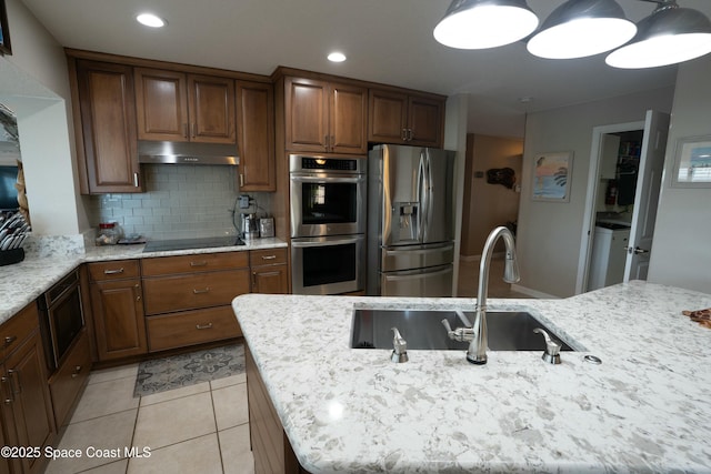 kitchen featuring stainless steel appliances, under cabinet range hood, decorative backsplash, and light stone counters