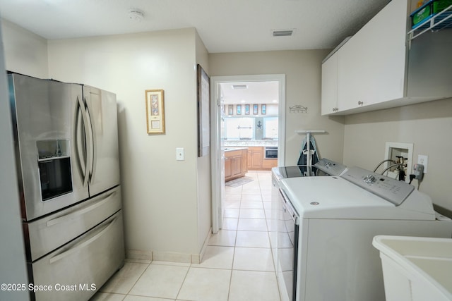 laundry area featuring washer and clothes dryer, a sink, light tile patterned floors, cabinet space, and visible vents