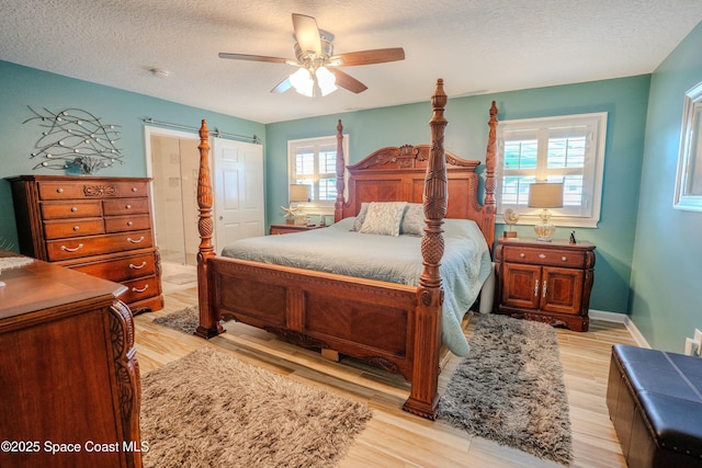 bedroom featuring light wood-style flooring, a textured ceiling, and a ceiling fan