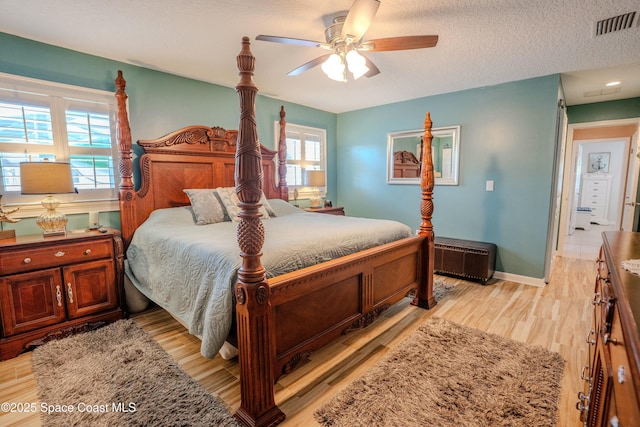 bedroom featuring a ceiling fan, a textured ceiling, light wood-style floors, baseboards, and visible vents