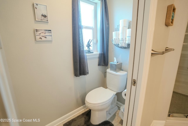 bathroom featuring baseboards, toilet, and plenty of natural light