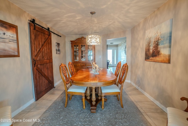 dining area featuring a barn door, baseboards, and light tile patterned floors