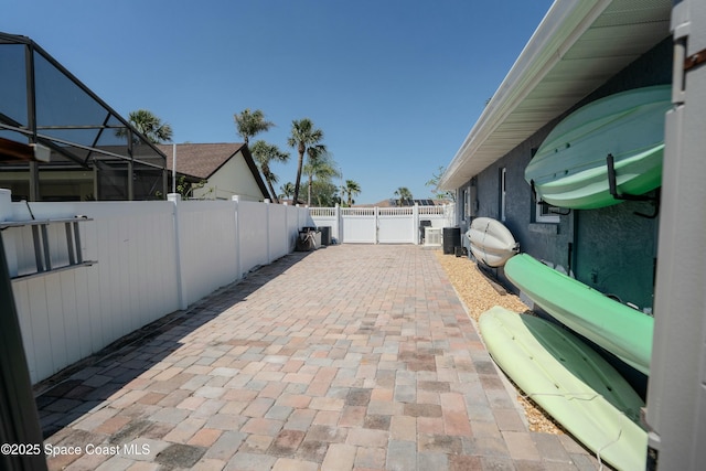 view of patio with a fenced backyard, glass enclosure, and central air condition unit