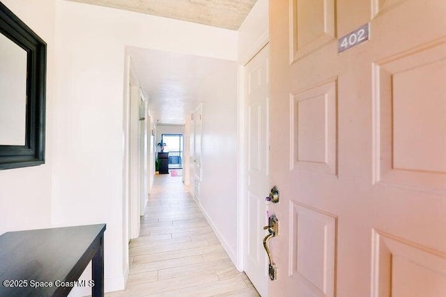 hallway with light wood-type flooring and baseboards