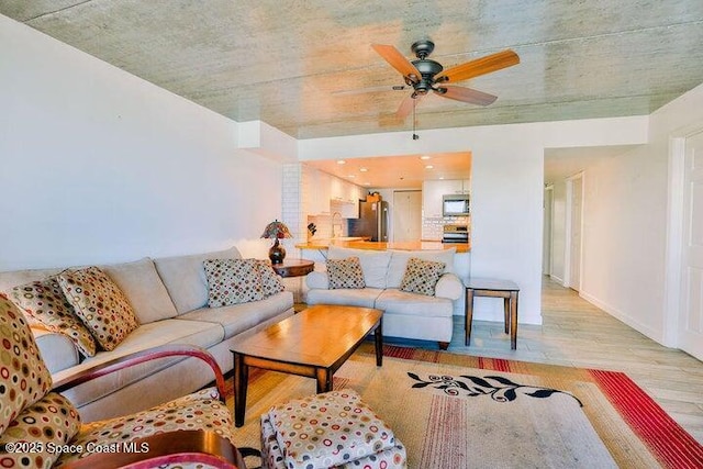 living area with wood finished floors, baseboards, and ceiling fan
