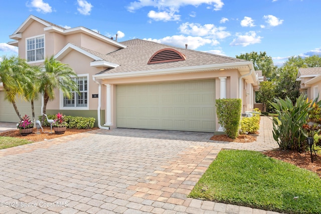 view of front of property with stucco siding, decorative driveway, a shingled roof, and an attached garage