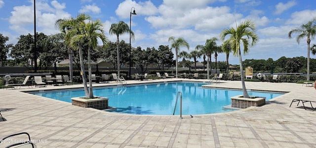 community pool with a patio and fence