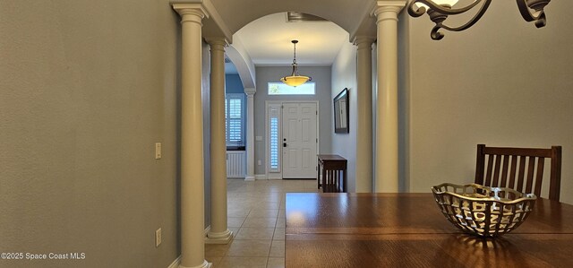 entryway with decorative columns, light tile patterned floors, baseboards, and arched walkways