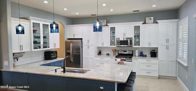 kitchen featuring hanging light fixtures, a sink, appliances with stainless steel finishes, and white cabinetry