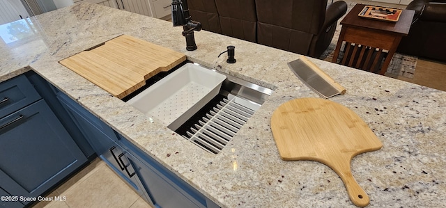 room details with a sink, light stone counters, and blue cabinetry