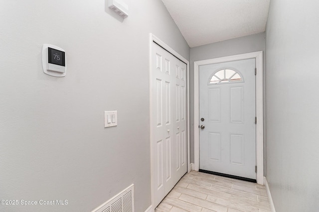doorway to outside with baseboards, visible vents, and light wood finished floors