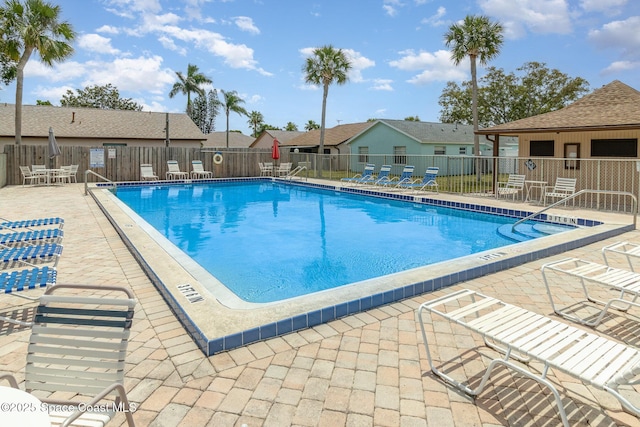 community pool featuring fence, a residential view, and a patio