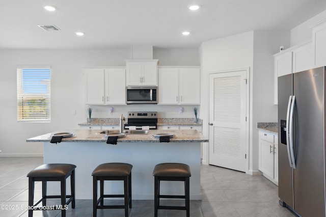 5358 Waterfall Pl, Grant, FL 32949 - kitchen featuring appliances with stainless steel finishes, a kitchen breakfast bar, white cabinets, light tile patterned flooring, and recessed lighting