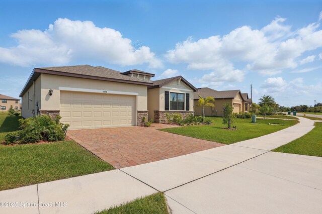 5358 Waterfall Pl, Grant, FL 32949 - view of front of home with stone siding, decorative driveway, a garage, a front lawn, and stucco siding