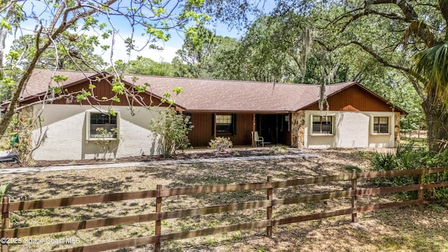 ranch-style home with fence, a porch, and a shingled roof