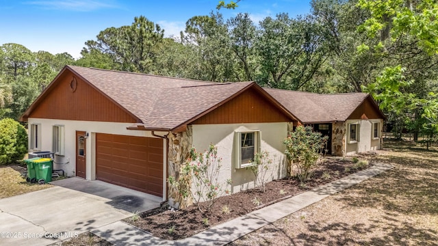 view of front of property featuring stucco siding, roof with shingles, concrete driveway, and an attached garage