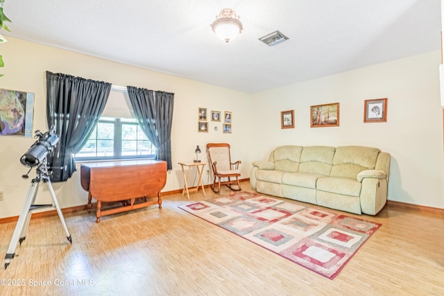 living room with wood finished floors, visible vents, and baseboards