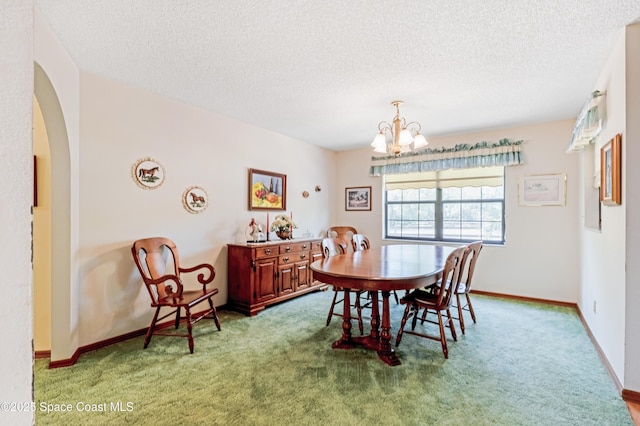 dining area featuring a chandelier, carpet floors, and a textured ceiling