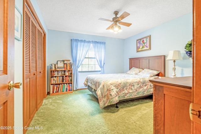 bedroom featuring a textured ceiling, a closet, a ceiling fan, and light carpet