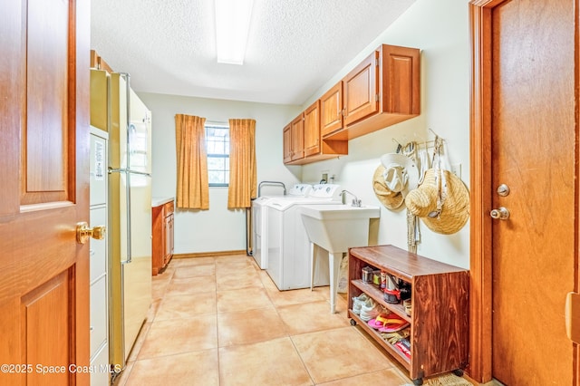 washroom featuring a textured ceiling, light tile patterned floors, cabinet space, and washing machine and dryer