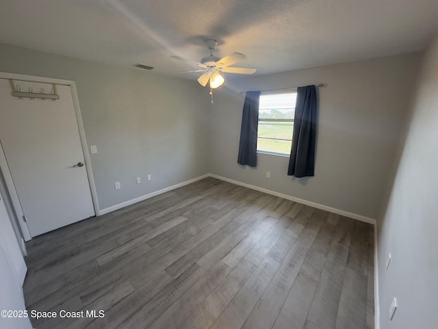 unfurnished room with wood finished floors, visible vents, a ceiling fan, and baseboards