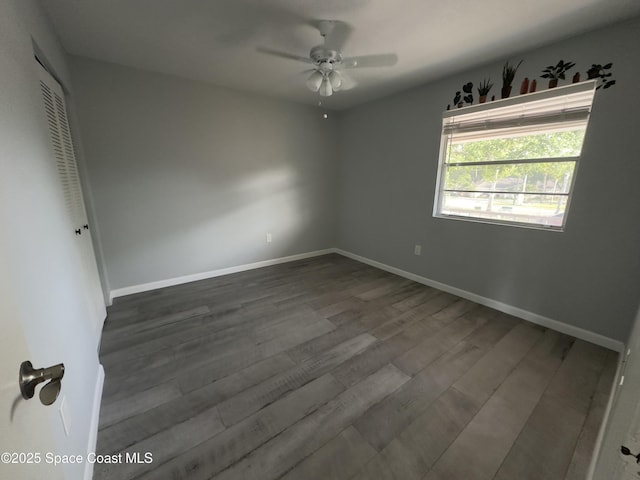 unfurnished bedroom featuring baseboards, a closet, a ceiling fan, and dark wood-style floors