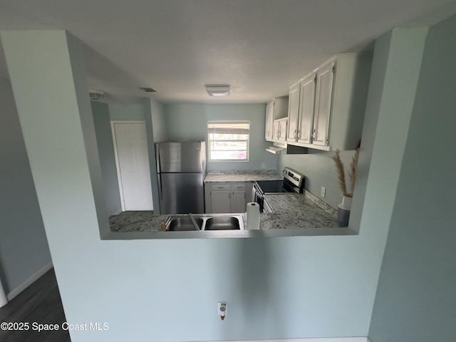 kitchen with white cabinets, stainless steel appliances, a peninsula, a sink, and light countertops