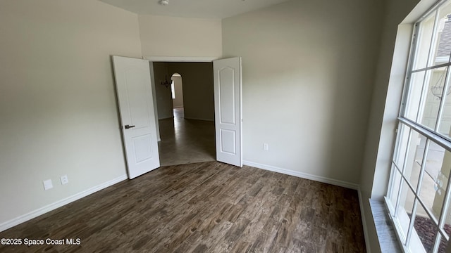466 Stonehenge Cir, Rockledge, FL 32955 - spare room featuring arched walkways, baseboards, and dark wood finished floors