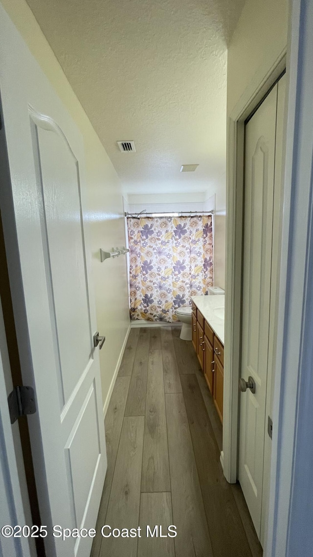 466 Stonehenge Cir, Rockledge, FL 32955 - full bathroom with vanity, toilet, a textured ceiling, visible vents, and hardwood / wood-style flooring