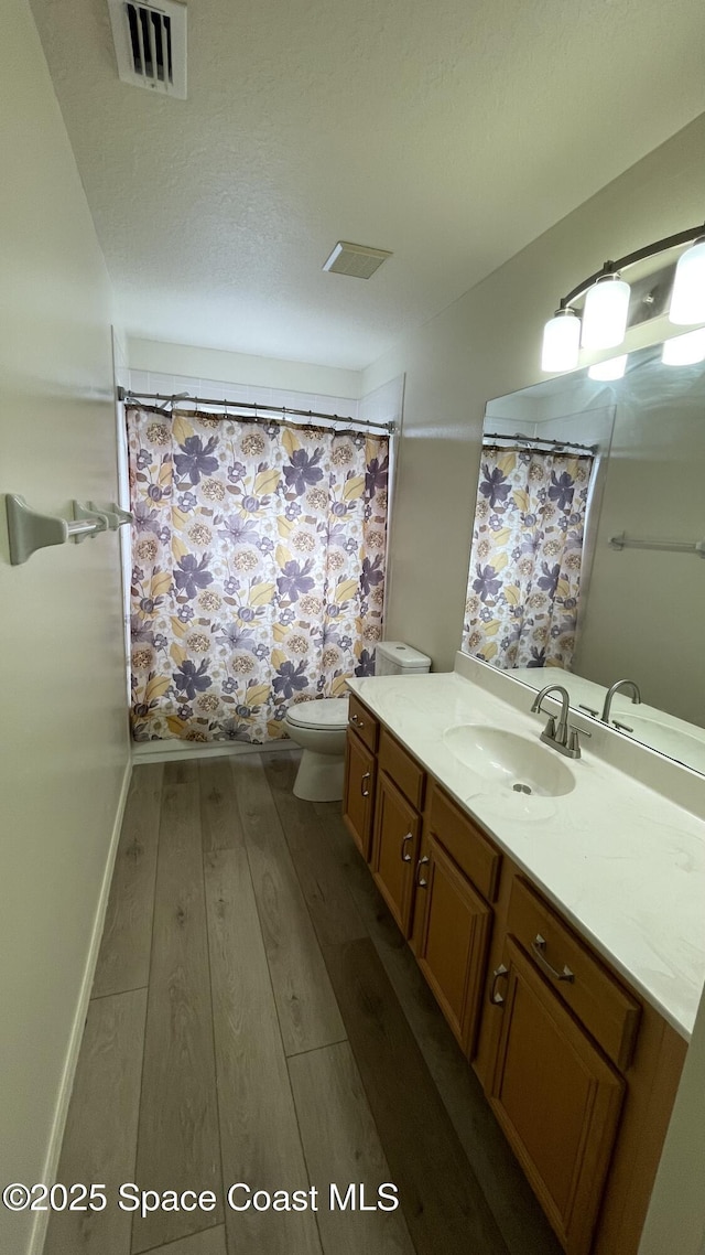 466 Stonehenge Cir, Rockledge, FL 32955 - bathroom with vanity, wood-type flooring, toilet, curtained shower, and visible vents