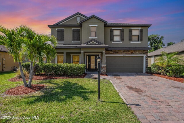 view of front of home with a garage, a front lawn, stone siding, stucco siding, and driveway