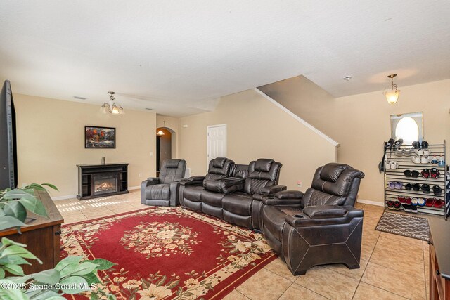 living room featuring arched walkways, a lit fireplace, light tile patterned flooring, and visible vents