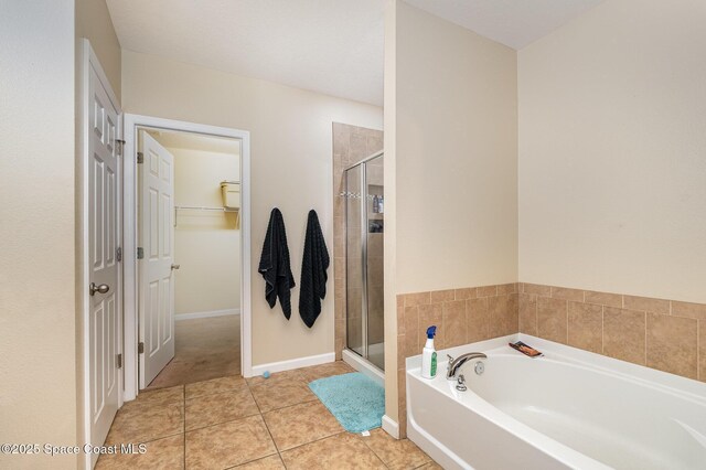 bathroom with tile patterned flooring, a walk in closet, a garden tub, and a stall shower
