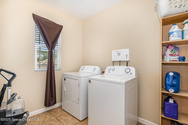 washroom featuring light tile patterned floors, baseboards, laundry area, and washing machine and clothes dryer