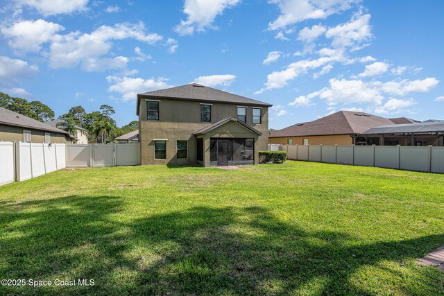 back of house featuring a sunroom, a fenced backyard, a lawn, and stucco siding
