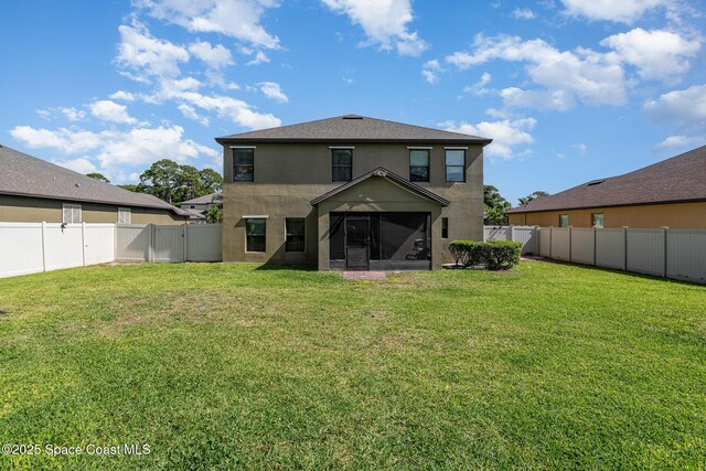 rear view of property featuring a yard, a fenced backyard, a sunroom, and stucco siding