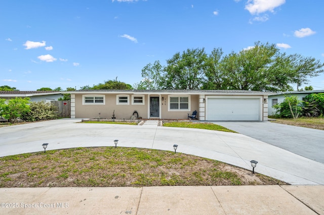 single story home featuring an attached garage, fence, curved driveway, and stucco siding